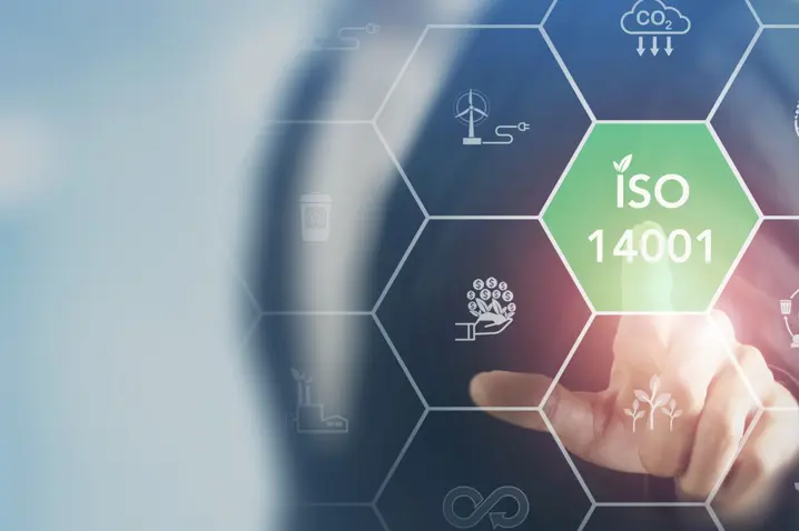 Hand pointing at glowing green hexagon labeled ISO 14001 with sustainability and environmental icons in futuristic interface.