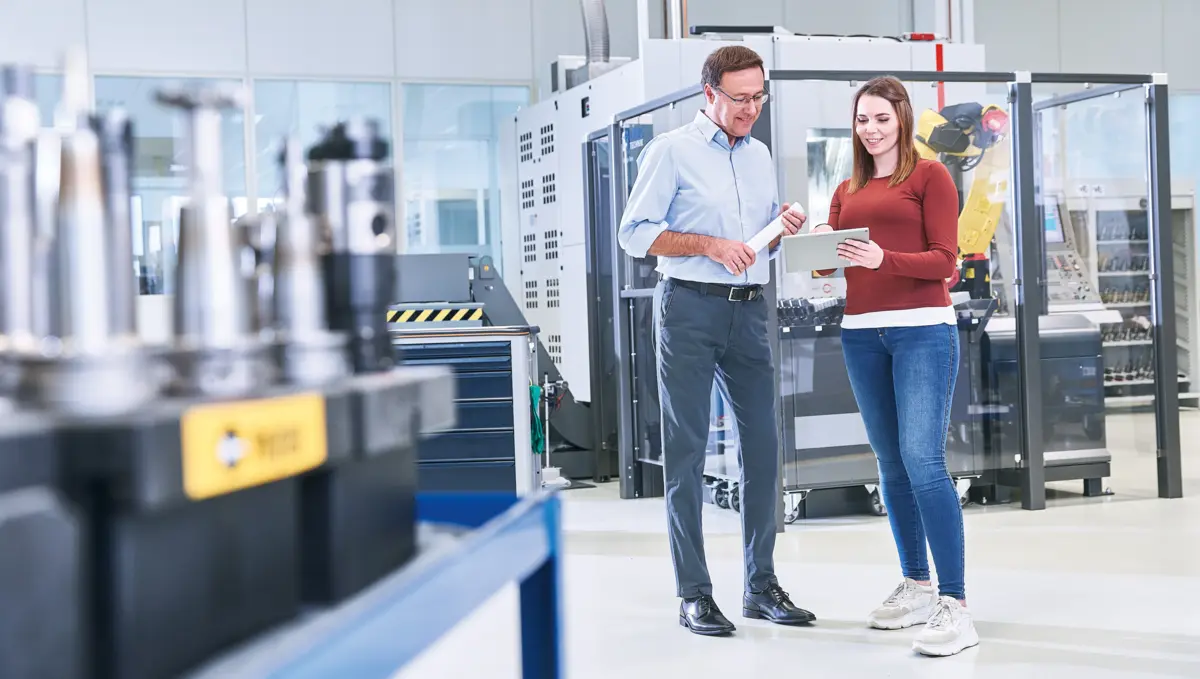 工厂车间内两位专业人士交流技术方案,展示高科技制造与团队协作氛围