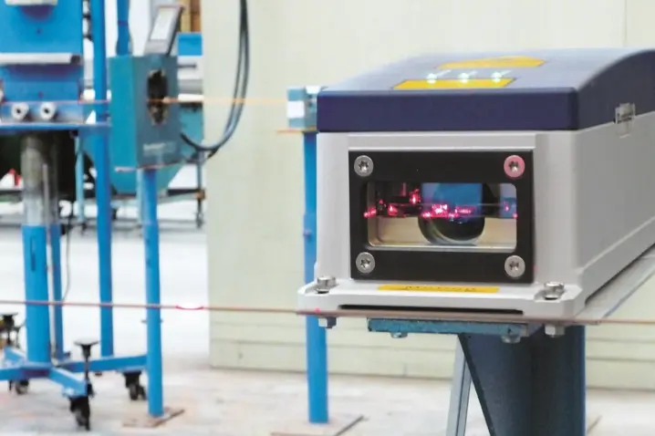 Polytec laser surface velocimeter measuring speed and length in industrial cutting with visible red laser beam for precise control.